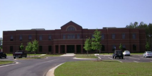 Photo of the brown brick front of the Shared Services Center building, including its parking lot, located in Sandersville, Georgia.